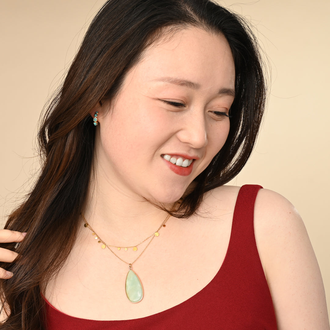 Woman wearing a red top and high quality fair trade layered necklaces with a beige background