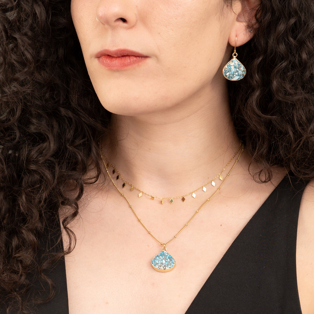 Woman wearing matching set of emperor stone necklace and earrings, shades of gold and blue, fair trade gift company, jewelry for women, surprises for Christmas presents