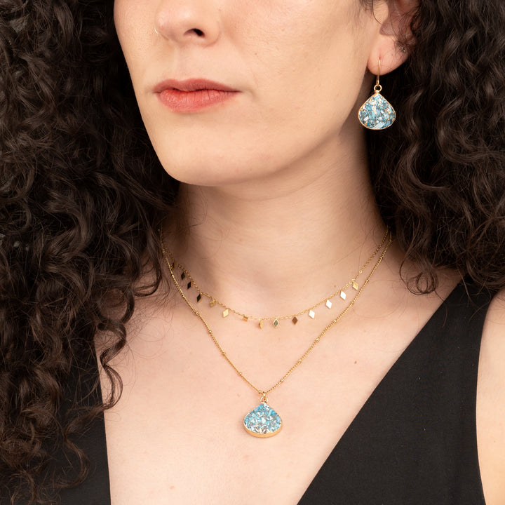 Woman wearing matching set of emperor stone necklace and earrings, shades of gold and blue, fair trade gift company, jewelry for women, surprises for Christmas presents