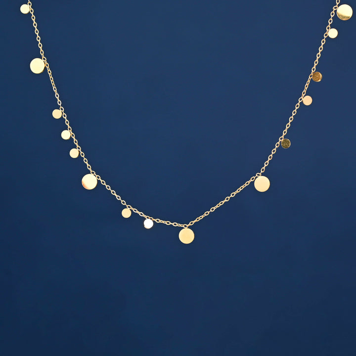 Photo of gold necklace with blue background, gold circles on necklace, ideas for Mother's day