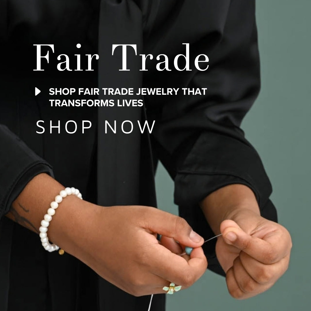 Hands threading a needle, wearing a pearl bracelet and gold ring, with the words "Fair Trade" and "Shop Now"