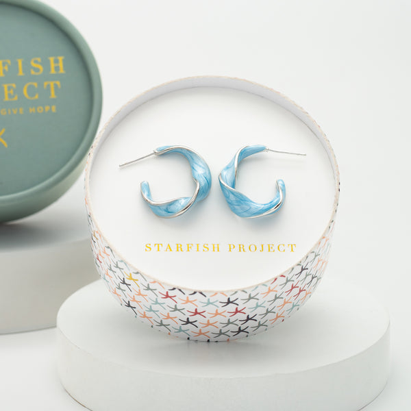 White gold and sky blue enamel hoop earrings by Starfish Project in a sound box with a colorful starfish pattern, ethical jewelry and a meaningful gift for women.