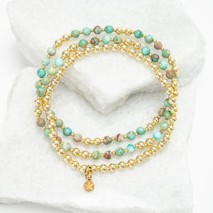 Stack of beaded bracelets with gold accents on a white marble surface, 18k gold plated beads, gold bracelet, sustainable fair trade women's jewelry
