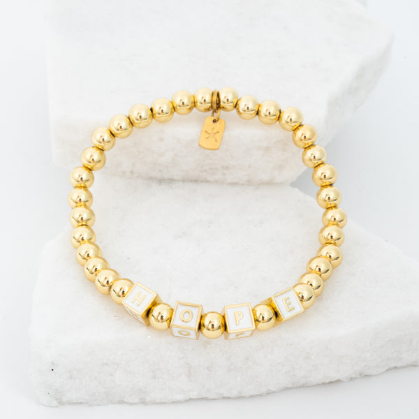 Photo of gold beaded bracelet, gold "hope" message, gold brass beads, symbol of hope, jewelry company like pandora