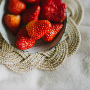 A photo of a bowl of strawberries set on beautiful handmade trivet, quality home decor